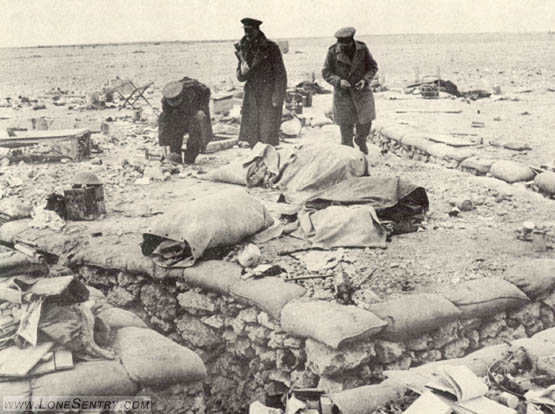 [Axis communication trenches were narrow and shallow, but carefully zig-zagged so as not to present an easy target for the British artillery. These British officers are inspecting equipment captured from the enemy.]